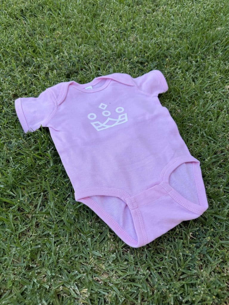 Pink custom logo baby onesie on grass