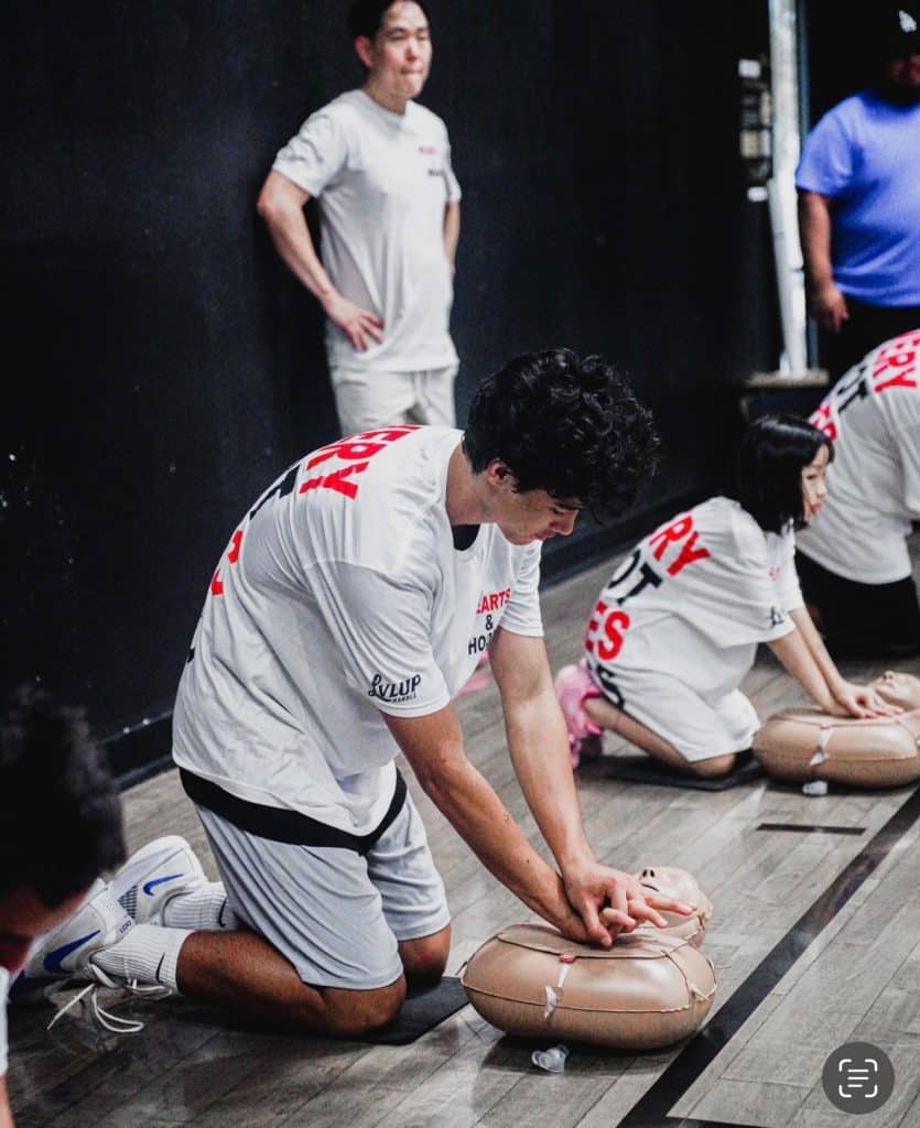Hearts and Hoops participant practicing CPR at community event