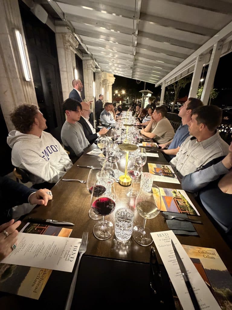 JNP team seated around a long dinner table with BLVD Steak and Cakebread Cellars menus