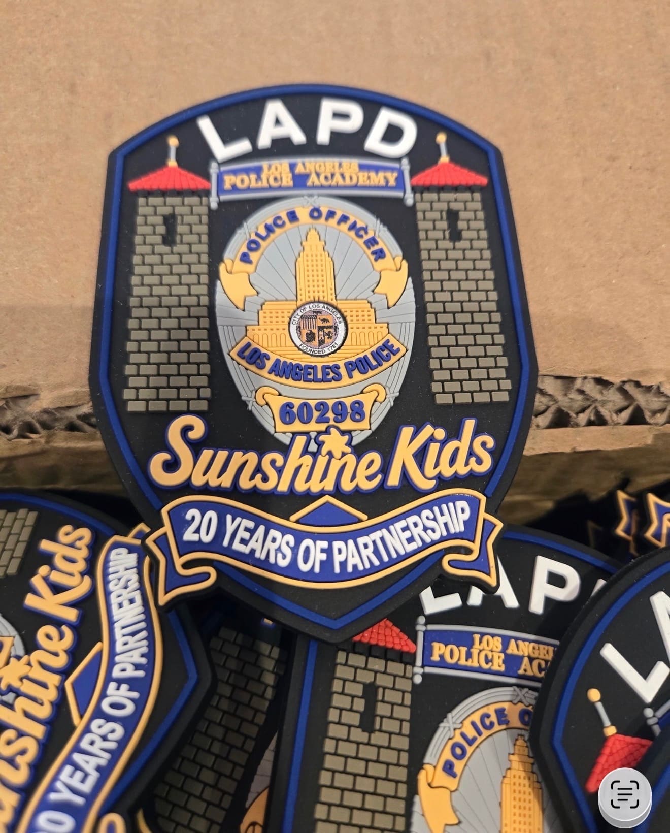Close-up of a badge-shaped LAPD and Sunshine Kids keepsake reading 20 Years of Partnership