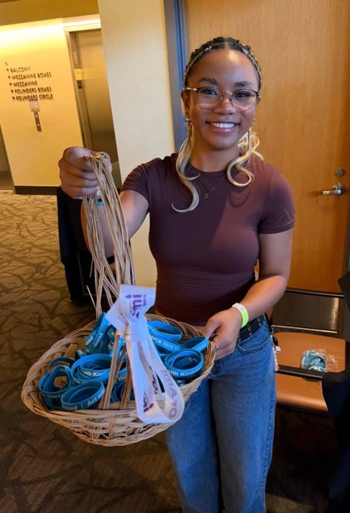 An attendee holding a basket of blue Chesed wristbands for the Congregation Or Ami gathering